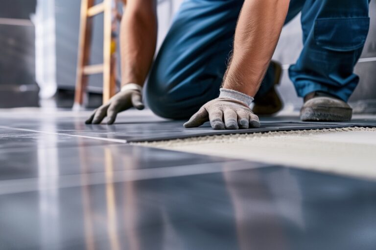 Fliesenleger verlegt Bodenplatten im Badezimmer